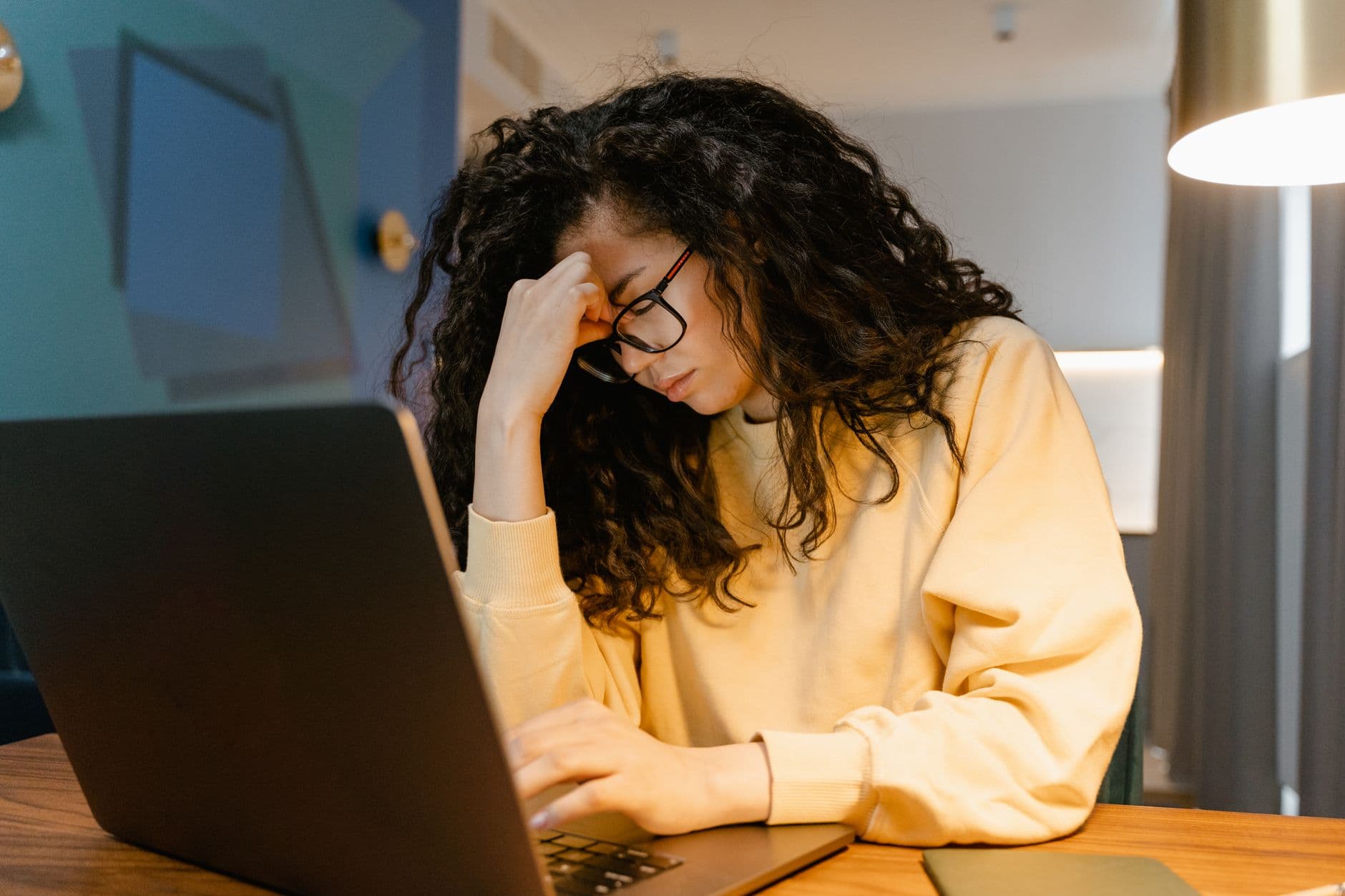 A desk worker pausing to stretch tall at their desk in afternoon light.