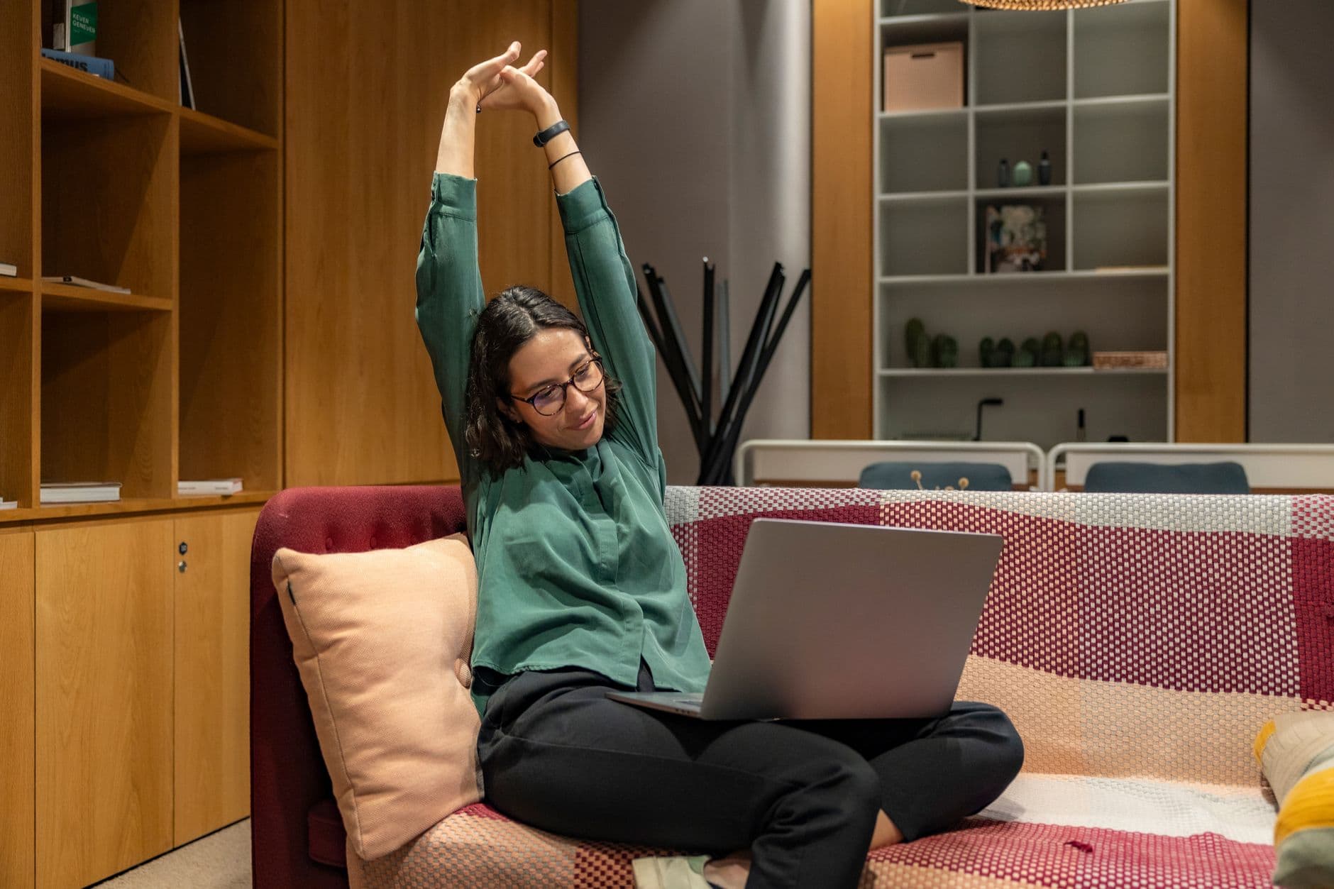 A person working on a laptop at a kitchen table, head tilted toward the low screen.